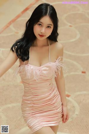 A woman in a pink dress posing on a staircase.