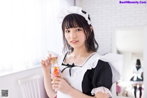 A woman in a maid outfit sitting on a chair.