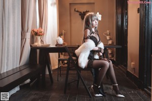 A woman in a black and white outfit sitting on a table.