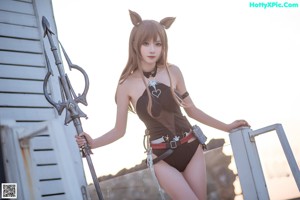 A woman in a bikini holding a trident on a dock.