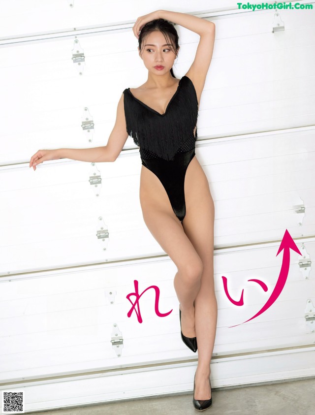 A woman in a black leotard posing in front of a garage door.