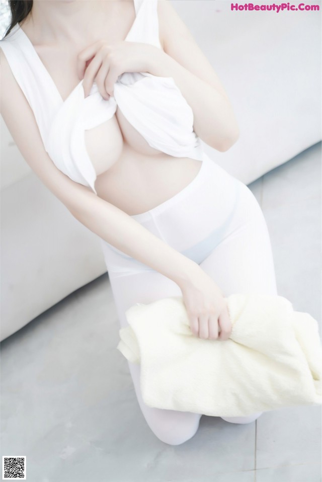 A woman in a white top and white pants holding a towel.