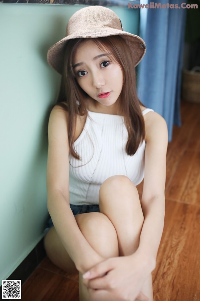 A woman in a straw hat sitting on the floor.