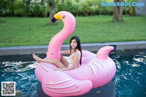 A woman in a pink bikini sitting on the edge of a pool.