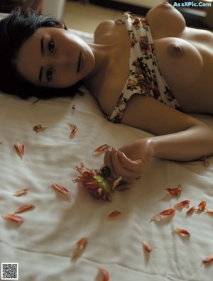A naked woman sitting in a field of tall grass.