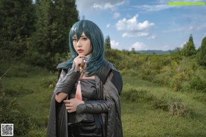 A woman with blue hair is posing naked on a rock.