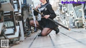 A woman in a school uniform crouching on the ground.