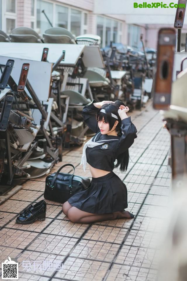 A woman in a school uniform sitting on the ground.