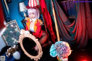 A woman in a red jacket and black stockings sitting on a chair.