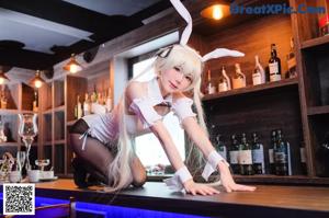 A woman in bunny ears sitting at a bar holding a glass of wine.