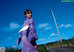 A woman in a blue and white kimono sitting on a chair.