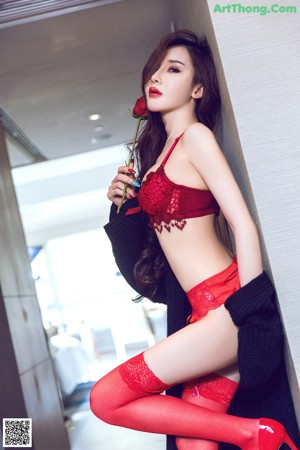 A woman in a red lingerie and stockings leaning against a mirror.