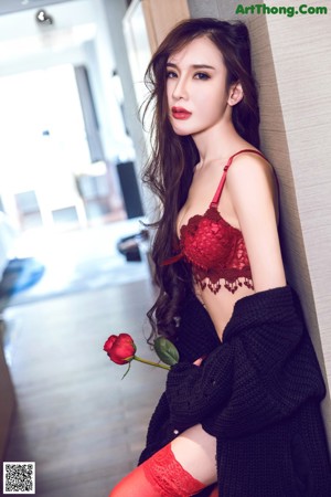 A woman in a red lingerie holding a rose.