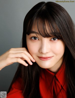 A woman in a red jacket is looking at the camera.