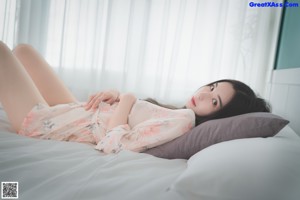 A woman laying on top of a bed in a white robe.