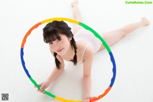 A young woman in a pink leotard holding a rainbow ribbon.