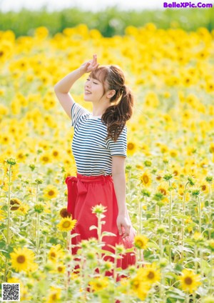 A woman in a red skirt holding up a striped shirt.