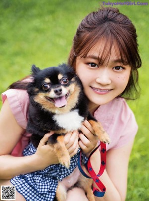 A woman walking a small dog on a leash.