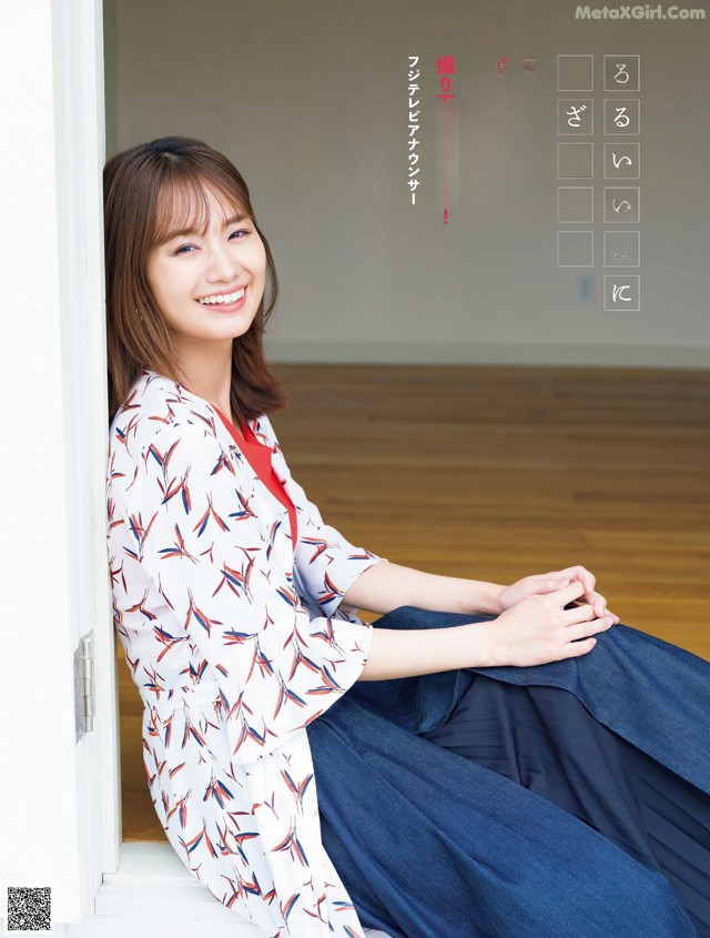 A woman sitting on the floor in front of a window.