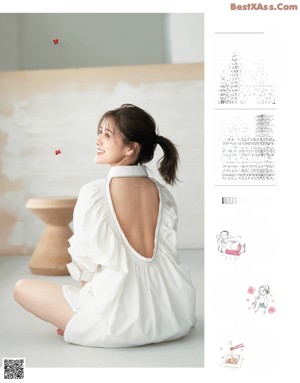 A woman in a white dress standing in front of a white wall.