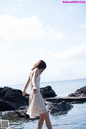 A woman standing in the water at the beach.