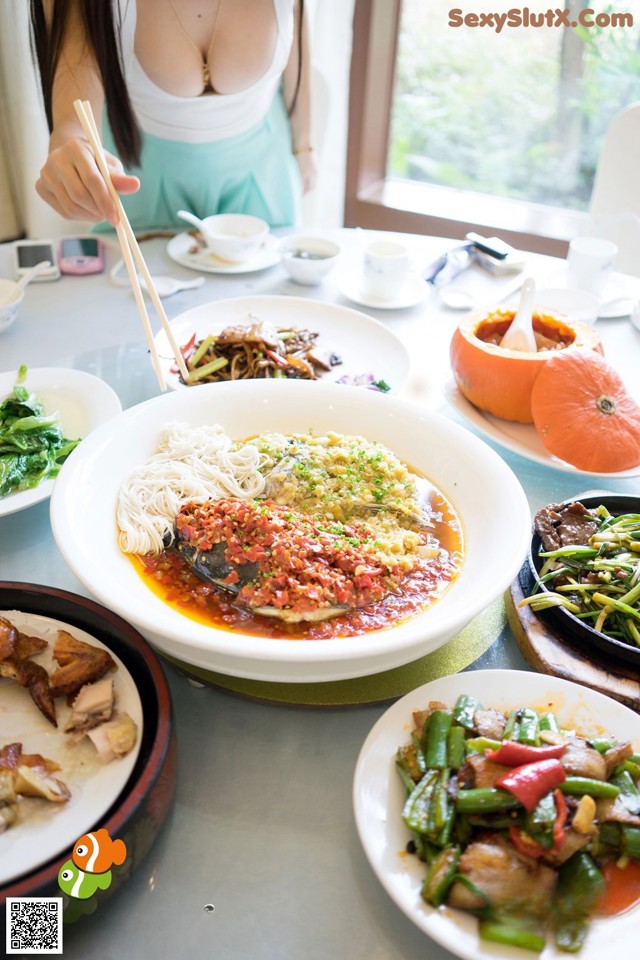 A woman sitting at a table with plates of food.