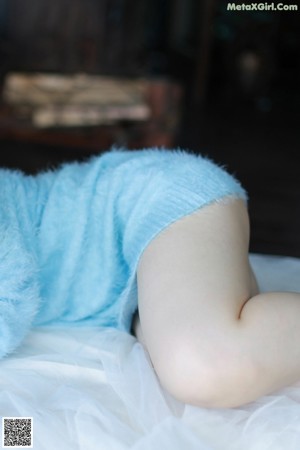 A woman in a blue dress laying on a bed.