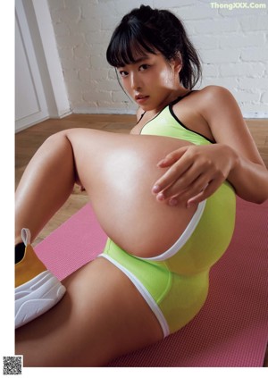 A woman in a yellow top and blue shorts is showing off her butt.