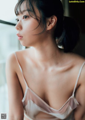 A woman in a pink lingerie sitting on a bed.