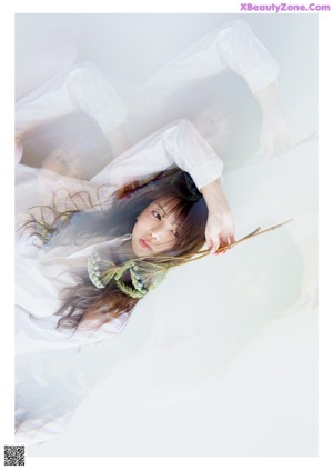 A naked woman laying on a wooden floor with her eyes closed.