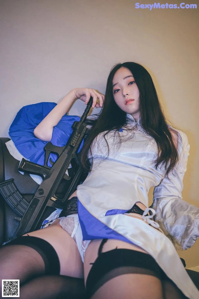 A woman in a white shirt and black stockings holding a gun.