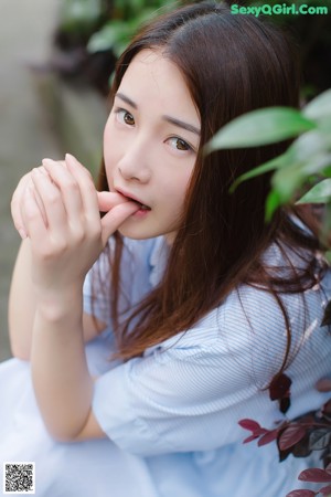 A woman sitting on the ground eating a slice of watermelon.