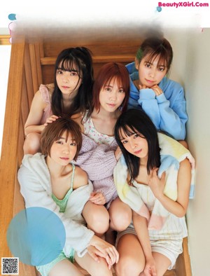 A group of young women sitting on top of a wooden bench.