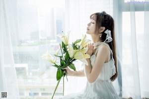 A woman in a white dress holding a bouquet of flowers.