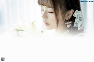 A woman in a white dress holding a bunch of white flowers.