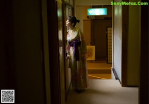 A woman in a kimono sitting by a window.