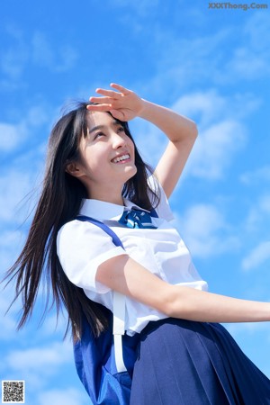 A woman in a blue tank top leaning against a fence.