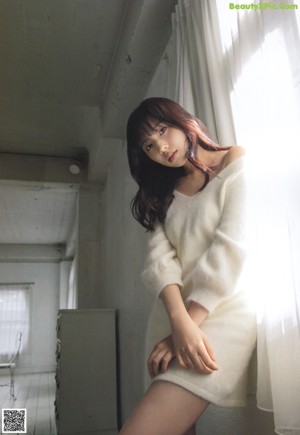 A woman sitting in a brown chair in front of a window.