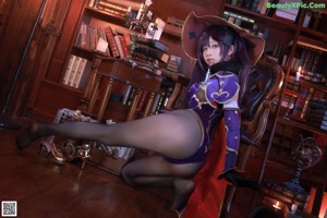 A woman sitting on a chair in front of a bookshelf.