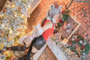 A woman sitting on a chair in front of a Christmas tree.