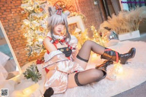 A woman sitting on the floor in front of a Christmas tree.